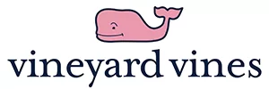 Vineyard Vines logo – A stylized pink whale and company name in blue against a white background. Vineyard Vines is a lifestyle brand known for its vibrant and preppy apparel. Offering a range of clothing, accessories, and more, Vineyard Vines captures the essence of relaxed elegance and embodies the joy of coastal living.