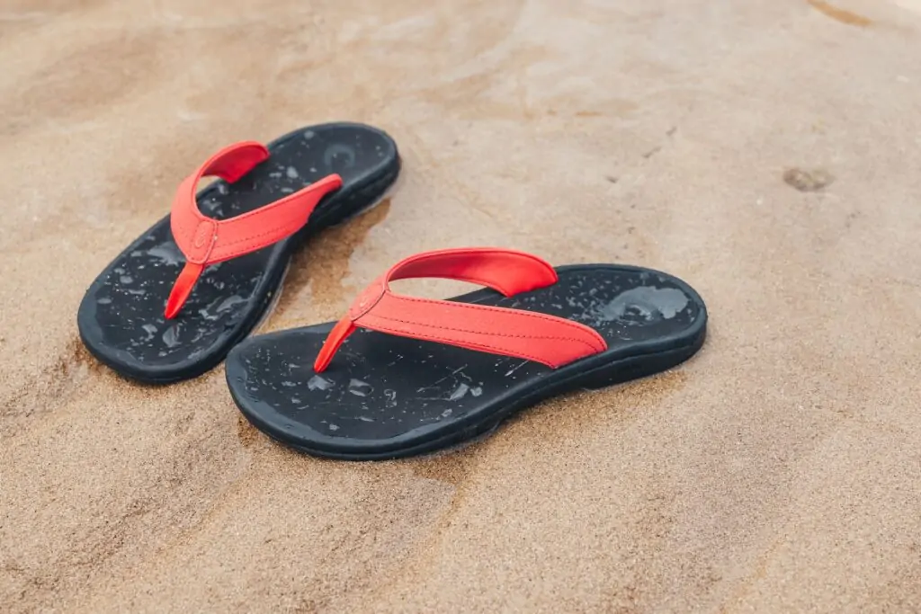 OluKai red and black flip-flops, perfect for active beach days in Panama City Beach.